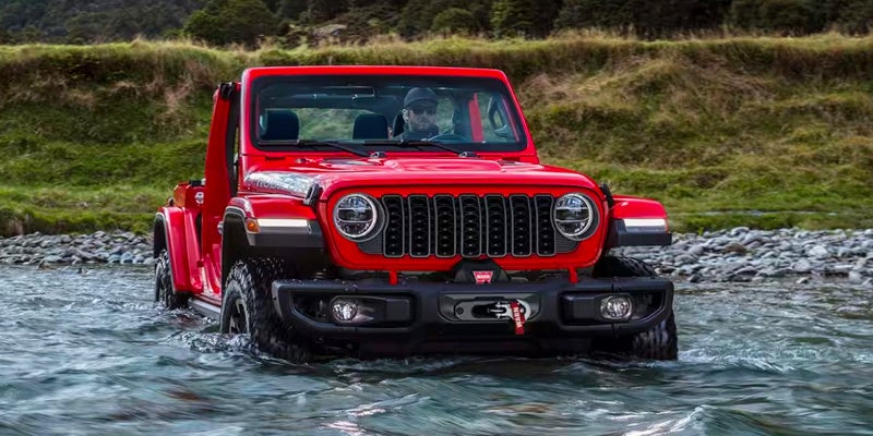 Red Jeep Wrangler driving through a river